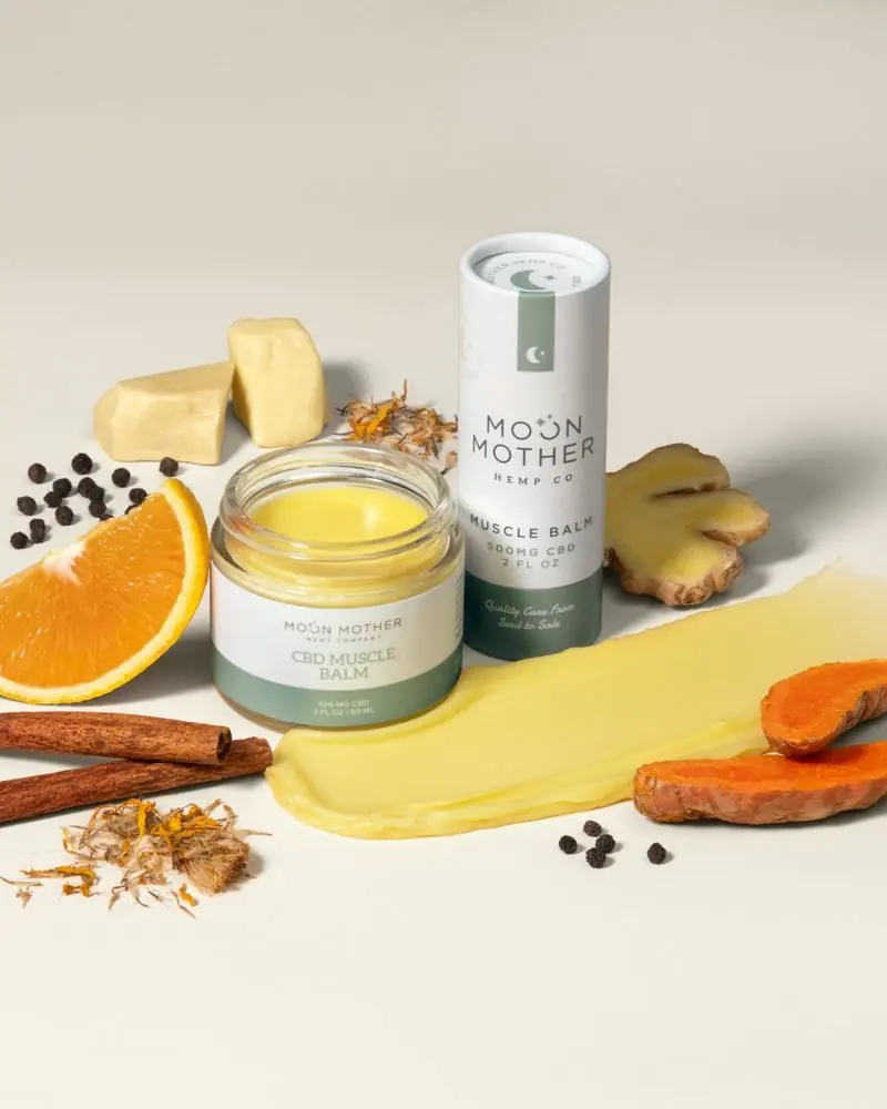 Orange, turmeric, ginger, cinnamon and calendula around a jar and tube of CBD Muscle Balm