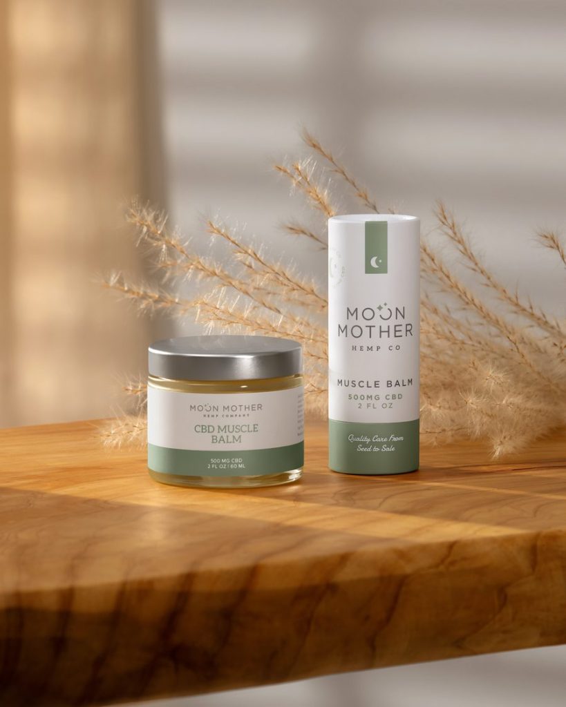 CBD Muscle Balm jar and stick on a sunlit wooden table