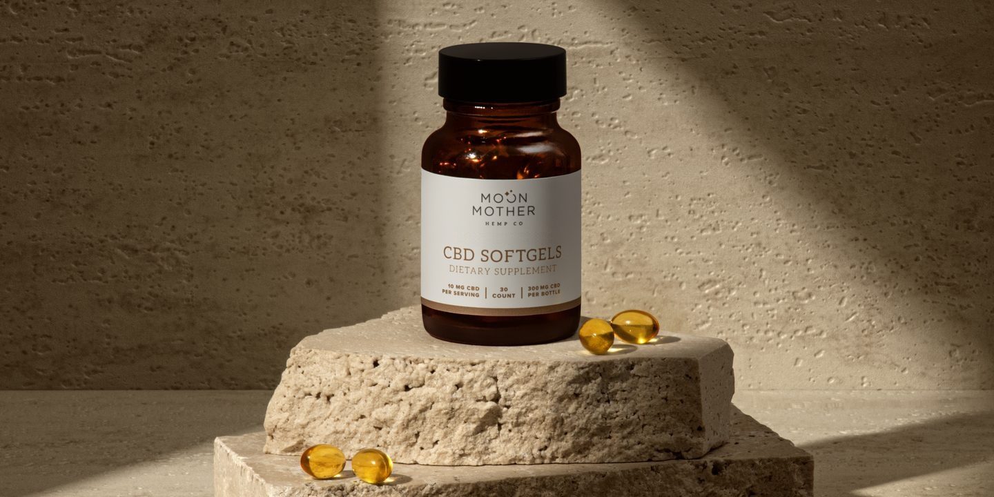 Hemp Oil CBD Softgels bottle on stone in afternoon light
