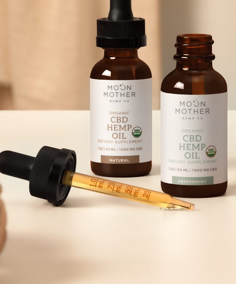 Dropper of golden hemp oil beside a tincture bottle