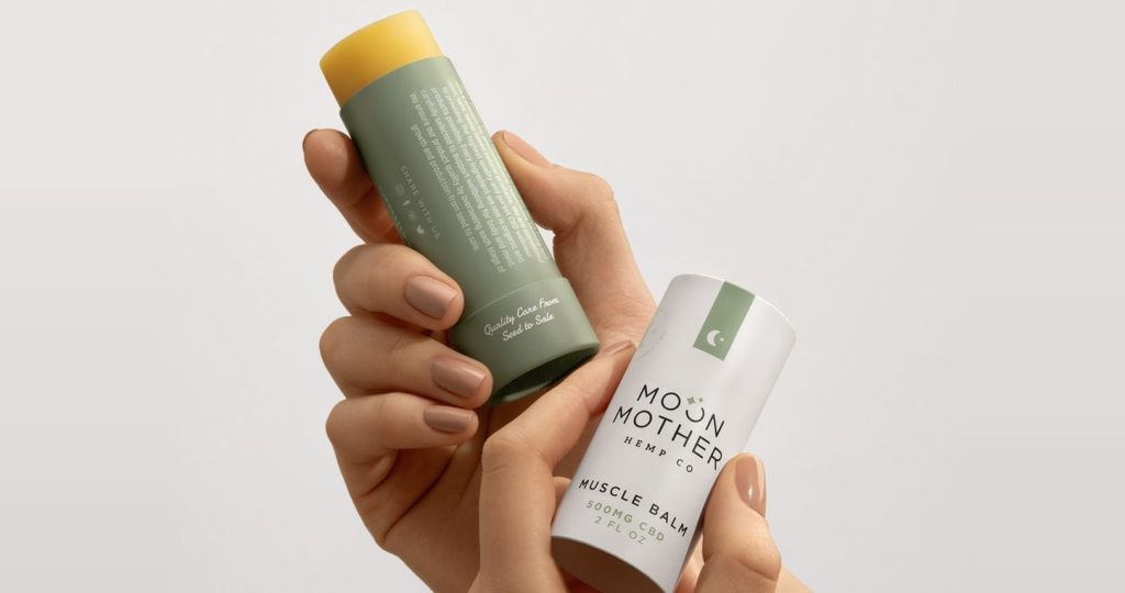 Hands holding a Moon Mother balm in its plastic-free paper tube