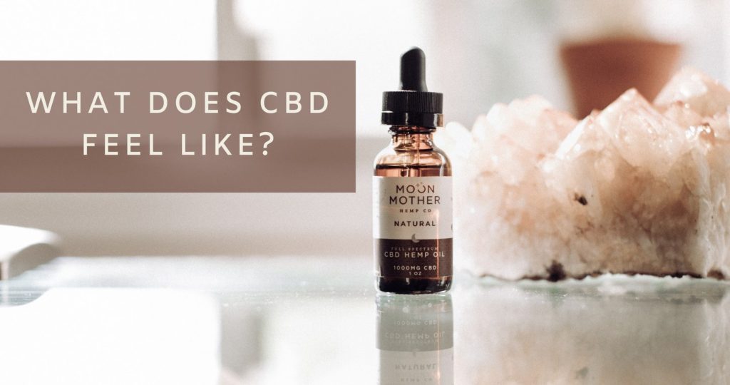 A Natural hemp oil tincture beside a rose quartz crystal, with the words What Does CBD Feel Like?